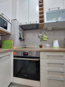 uma cozinha com armários brancos e um forno preto em Nice apartment near Old Town and sea em Budva