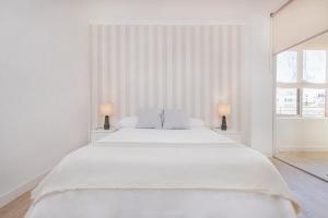 - une chambre blanche avec un grand lit blanc et deux lampes dans l'établissement Marbella center Casals, à Marbella