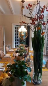 LA LANDE في Pleyber-Christ: طاولة غرفة الطعام مع إناء من الزهور عليها