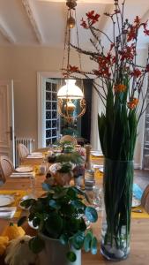 a dining room table with a vase of flowers on it at LA LANDE in Pleyber-Christ