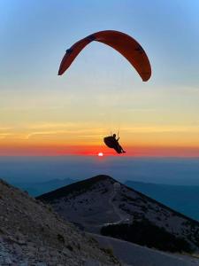 une personne en parachute survolant une montagne dans l'établissement Chambres entre Ventoux et luberon, à Sault