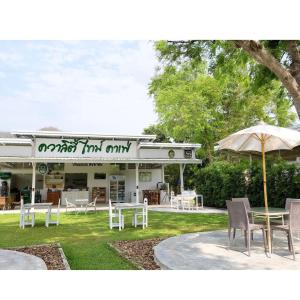un restaurante con mesas y una sombrilla en el césped en Quality Time farm stay: Yard house, en Ban Pa Lau