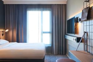 um quarto de hotel com uma cama e uma televisão em Moxy Brussels City Center em Bruxelas