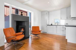 Duas cadeiras cor-de-laranja numa sala de estar com lareira em Nappstraumen Seafront Cabin, Lilleeid 68 em Gravdal