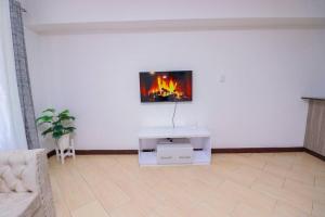 een woonkamer met een tv aan een witte muur bij Shyrah Havana in Nairobi
