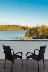 two chairs on a deck with a view of a lake at Ferienhaus am Tramser See in Trams