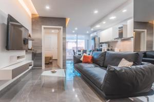 a living room with a black couch and a tv at Chic Retreat in the Heart of Tigne Sliema in Sliema