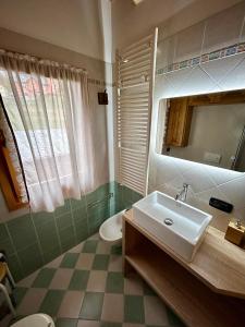 een badkamer met een wastafel, een toilet en een spiegel bij Auronzo - appartamento centrale vista mozzafiato in Auronzo di Cadore