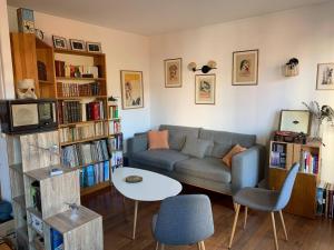 ein Wohnzimmer mit einem Sofa und einem Tisch in der Unterkunft Chambre privée au calme chez l'habitant in Montrouge