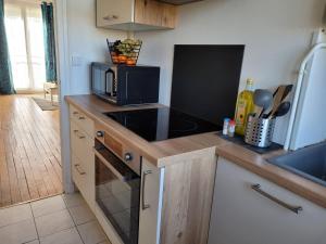 a kitchen with a microwave and a stove top oven at La Compiègnoise - Spacieux - Lumineux - Cosy in Compiègne