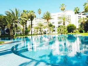 a large swimming pool with palm trees and a building at Luxe en bord de mer à la Marina d'Agadir in Agadir