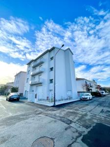 un edificio blanco con coches estacionados en un estacionamiento en Donnino Apartments, en Fidenza