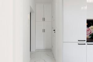 a white kitchen with white cabinets and marble floors at Elite Apartments Sopot Comfort in Sopot