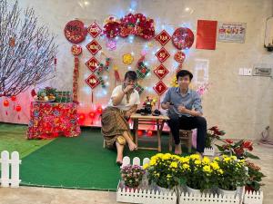 two people sitting at a table in a room with flowers at COZY Hotel HCM in Ho Chi Minh City