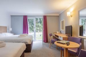 a hotel room with two beds and a desk at The Broadway Park Hotel in Sandown