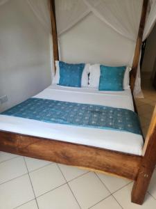 un letto con cuscini blu in una stanza di Pendo Villas Diani Beach a Diani Beach