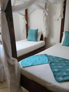 two beds in a room with blue pillows at Pendo Villas Diani Beach in Diani Beach