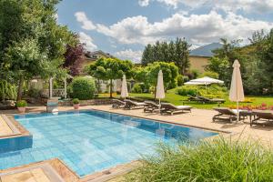 a swimming pool with chairs and umbrellas in a yard at Hotel Bismarck in Bad Hofgastein