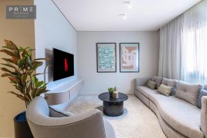 a living room with a couch and a tv at Prime Residence Sheikh Zayed in Sheikh Zayed