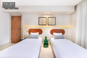 two beds in a hotel room with white walls at Prime Residence Sheikh Zayed in Sheikh Zayed