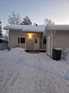 una casa está cubierta de nieve con una entrada en 2BR and LuxurySauna, en Tornio