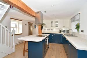 a large kitchen with blue cabinets and a sink at Impeccable 2-Bed Cottage in Johnshaven in Montrose