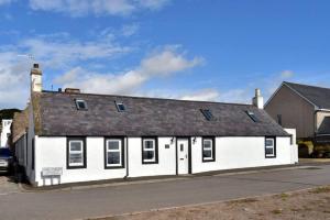a white building with a black roof at Impeccable 2-Bed Cottage in Johnshaven in Montrose