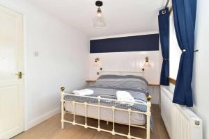 una piccola camera da letto con letto e tende blu di Impeccable 2-Bed Cottage in Johnshaven a Montrose