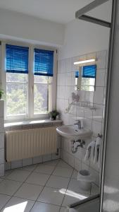 La salle de bains est pourvue d'un lavabo, d'une baignoire et de fenêtres. dans l'établissement Gästehaus Wilsickow, à Lübbenow