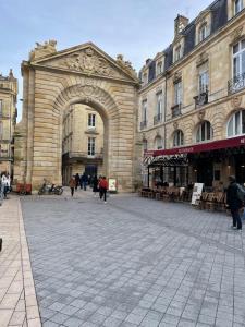 um grande edifício com um arco numa rua em Le COSY - Rue Ausone em Bordeaux