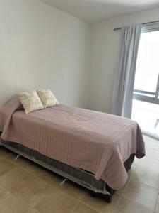 a bed in a white room with a window at Duplex 3/4 pers. en hermosa zona in Guaymallen