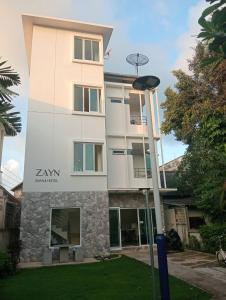 Ein hohes weißes Gebäude mit einem Schild drauf. in der Unterkunft ZAYN Samui Hotel in Bophut 