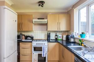 a kitchen with wooden cabinets and a white stove top oven at Spacious 2BD House wPrivate Garden - Kennington! in London