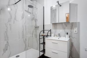 uma casa de banho branca com um chuveiro e um lavatório. em Au charme d'antan - Un joyau caché em Troyes