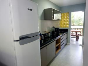 uma cozinha com um frigorífico branco num quarto em Apê Varanda Gourmet Wi-fi 300mbs Garagem Arcondiconado Cozinha completa Streaming em Mata de Sao Joao