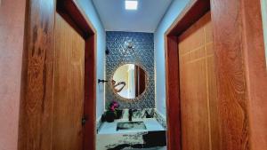 uma casa de banho com um lavatório e um espelho em Apê Varanda Gourmet Wi-fi 300mbs Garagem Arcondiconado Cozinha completa Streaming em Mata de Sao Joao