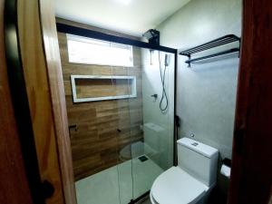 uma casa de banho com um WC e uma cabina de duche em vidro. em Apê Varanda Gourmet Wi-fi 300mbs Garagem Arcondiconado Cozinha completa Streaming em Mata de Sao Joao