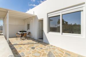 a white house with a patio with a table and chairs at Andriana's cycladic house close to the sea in Drios