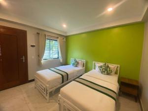 two beds in a room with a green wall at Kep Orchid Boutique Resort in Kep