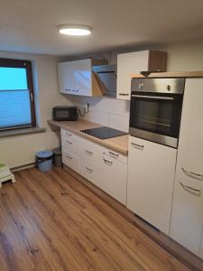a kitchen with white appliances and a wooden floor at Ferienwohnung Schulze in Hohenwestedt