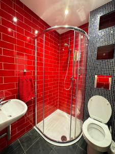 W wyłożonej czerwonymi kafelkami łazience znajduje się prysznic i toaleta. w obiekcie Spacious 4BD Family Home with GardenKensal Green! w Londynie