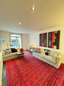 salon z 2 kanapami i czerwonym dywanem w obiekcie Spacious 4BD Family Home with GardenKensal Green! w Londynie