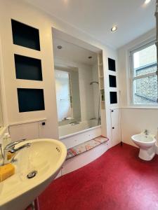 a bathroom with a sink and a toilet and a mirror at Spacious 4BD Family Home with GardenKensal Green! in London