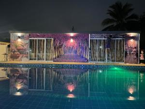 a swimming pool at night with a painting on the wall at วิลล่าพอใจ in Chiang Mai