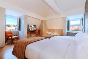 a hotel room with two beds and a television at Lisboa Carmo Hotel in Lisbon