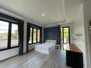 une chambre avec un lit, un bureau et des fenêtres dans l'établissement วิลล่าพอใจ, à Chiang Mai 29 autres photos