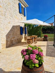 een patio met een tafel, een parasol en bloemen bij Villa Laura - Home Away From Home in Labin