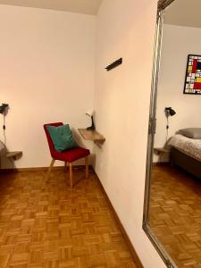 a room with a red chair and a mirror at Central 2 bedroom flat in heart of Eaux-vives in Geneva