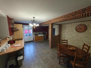 une cuisine et une salle à manger avec une table et une horloge dans l'établissement Gite de la Guernouille, à Luçay-le-Mâle