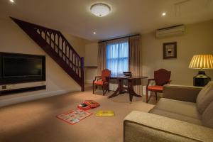 a living room with a couch and a tv and a table at Ettington Park Hotel, Stratford-upon-Avon in Stratford-upon-Avon